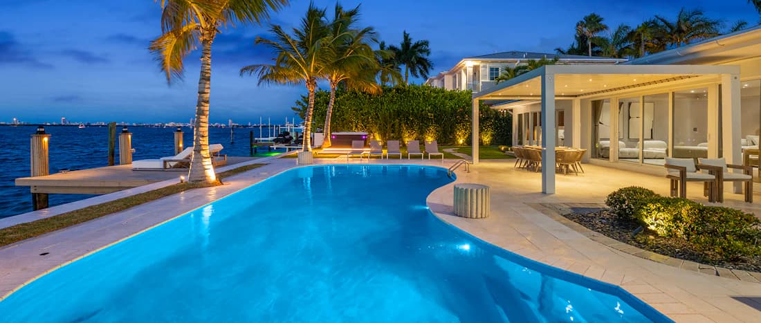 A waterfront terrace and swimming pool at dusk